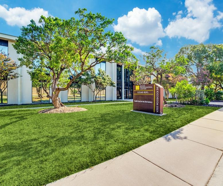 Exterior view of the white facade and landscaped grounds at 4203 Woodcock Drive.