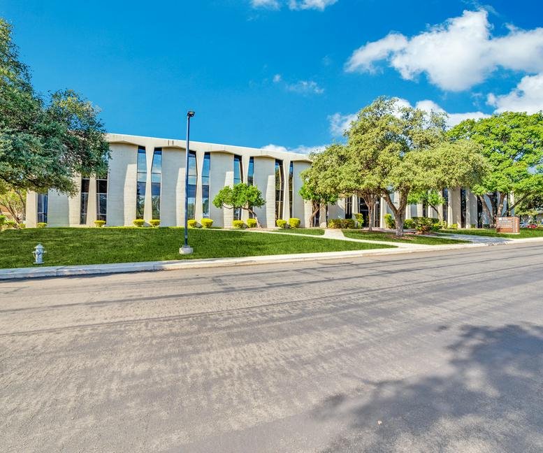 Exterior view of the modernist building with unique arched window frames at 4242 E Piedras Dr, San Antonio, Texas.