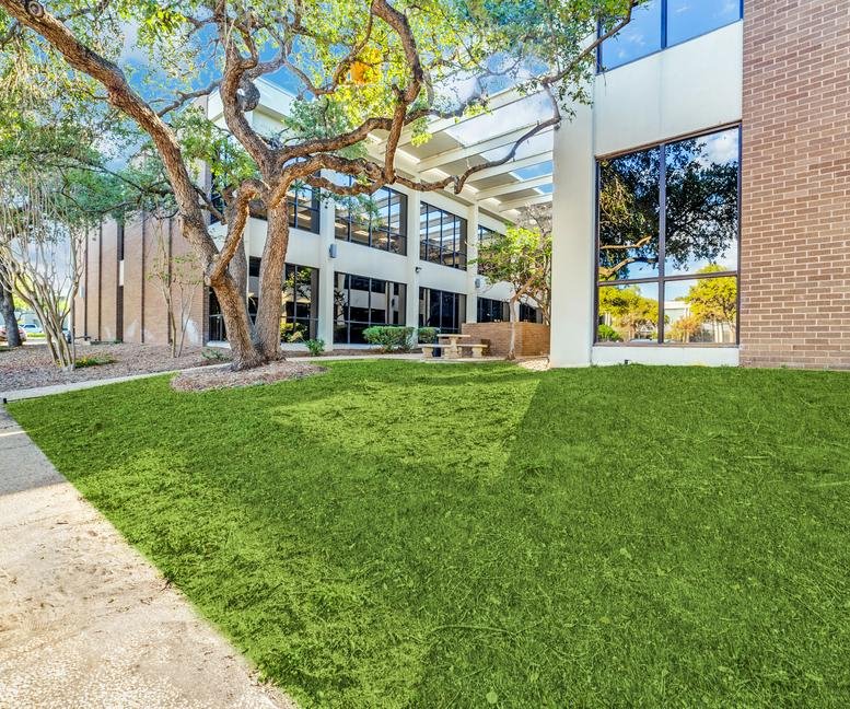 Exterior facade of 4242 Woodcock Drive featuring large windows and a manicured green lawn.