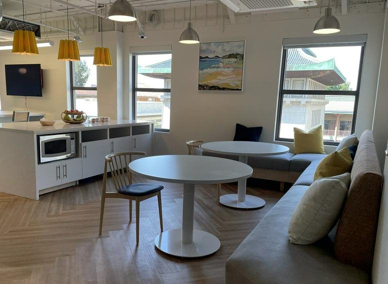 Spacious communal lounge at 428 J St, 4th Floor, featuring round tables, a kitchenette, and large windows.