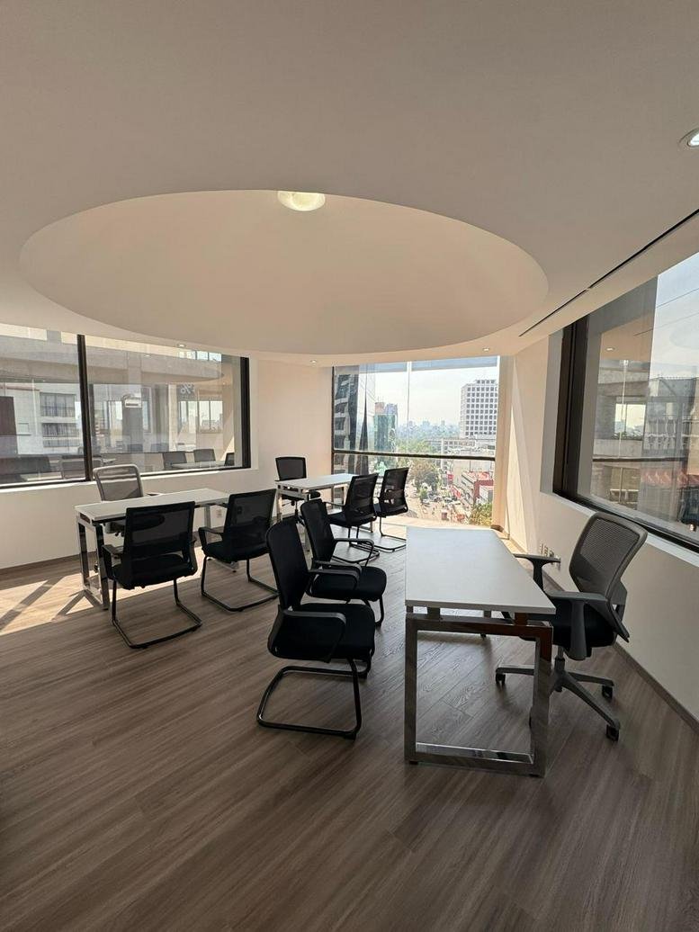 Spacious sunlit coworking area with modern workstations and city views at 4322, Calzada Lázaro Cárdenas.