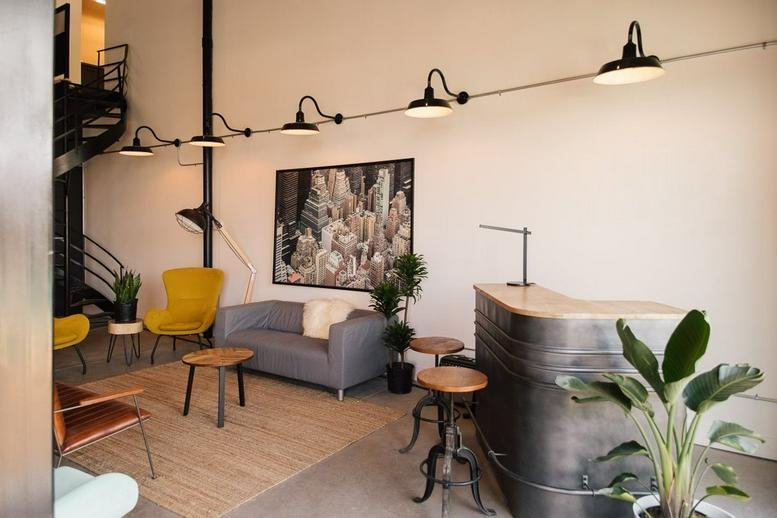 Spacious reception area with a metal desk, yellow armchairs, and art at 4422-A Louis B. Mayer, Laval, Quebec.