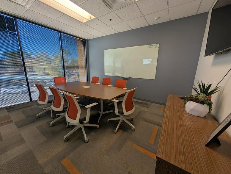 Spacious meeting room at 443 East Chandler Boulevard Suite 200 with orange chairs and a large whiteboard.