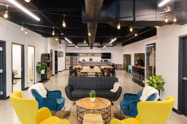 Spacious communal lounge and coworking area at 4430 Rue Garand, Laval, Quebec, with modern seating and industrial ceiling.