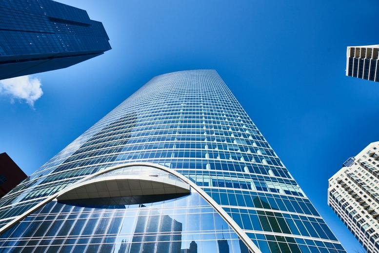 Low angle landscape shot of the glass skyscraper against a bright blue sky.