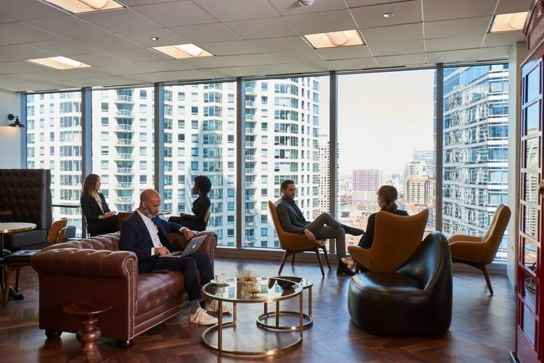 Sunlit lounge area with comfortable leather sofas and floor-to-ceiling city views.