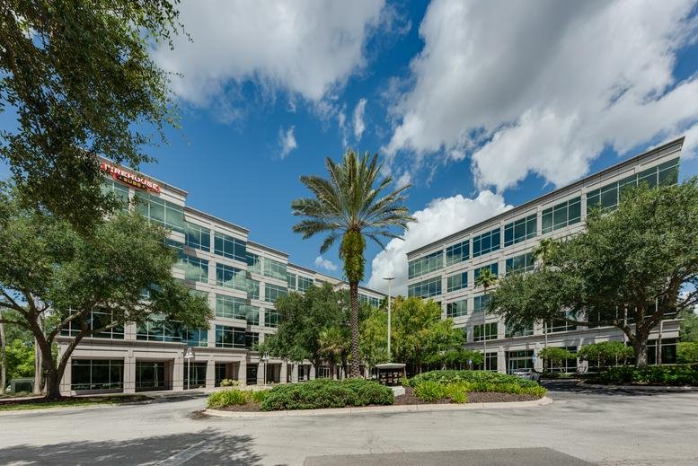 Wide exterior shot showing the multi-story office complex facade and palm trees.