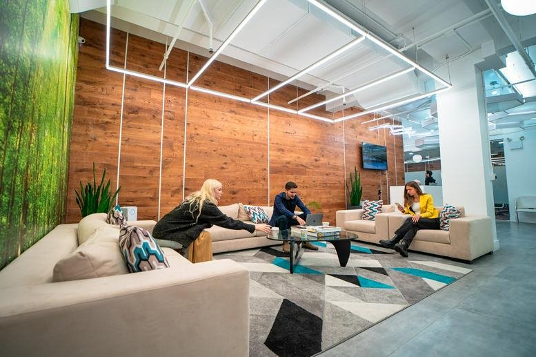 Modern communal lounge with a wood-paneled feature wall, plush sofas, and a geometric rug.