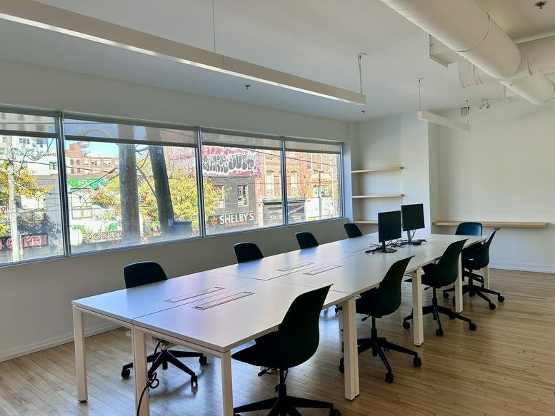 Spacious open-plan workspace at 485 Queen Street West with large windows and white desks.