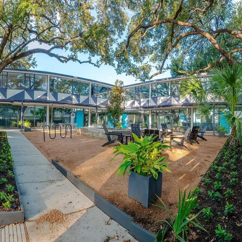 Landscaped courtyard at 4900 Travis Street featuring outdoor seating and mature oak trees.