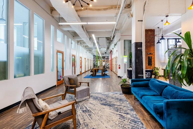 Spacious lounge at 495 Flatbush Avenue with a plush blue velvet sofa and stylish armchairs.