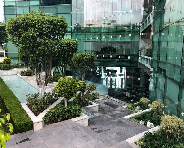 Modern glass office building with a landscaped garden and stone pathways.