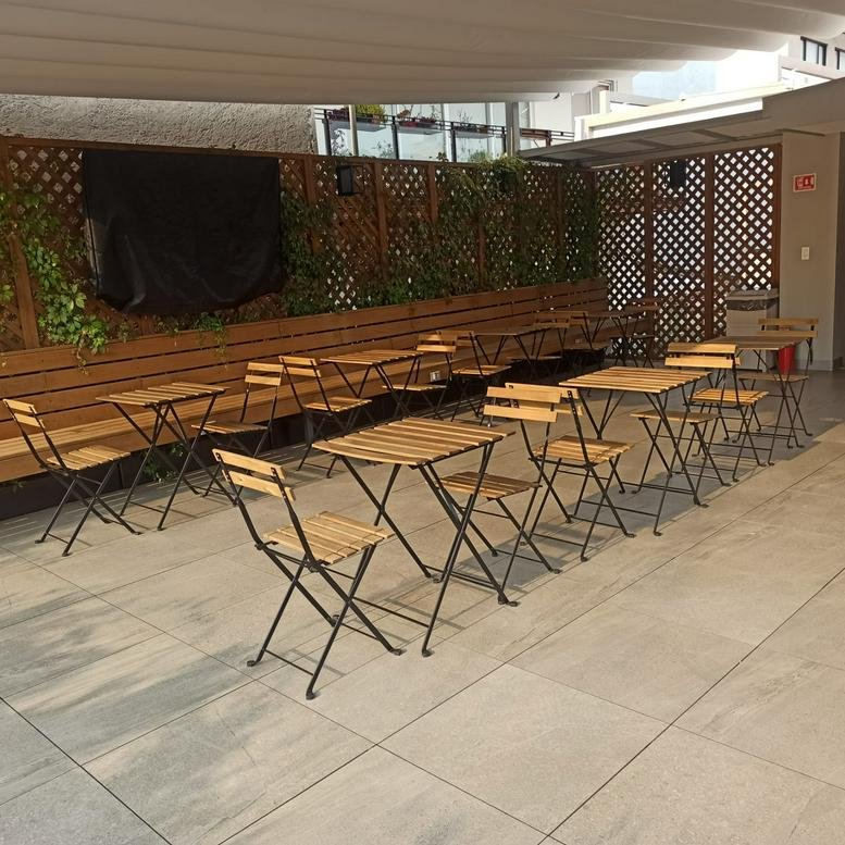 Outdoor terrace with rows of wooden bistro tables and chairs under a white canopy.