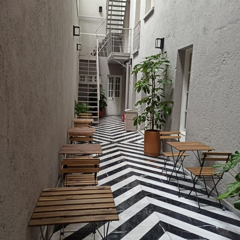 Narrow courtyard with a bold chevron-patterned floor and small cafe tables.
