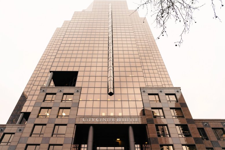 Exterior view of the glass-facade City Center Bellevue building against a bright sky.