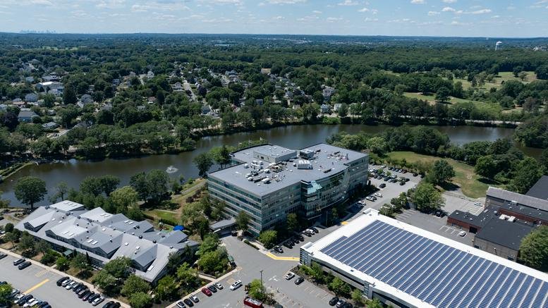 Aerial view of the multi-story 500 Cummings Center building surrounded by greenery and water.