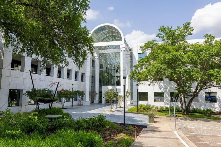 Exterior view of the white facade and arched glass entrance at 5000 Plaza on the Lake Drive.