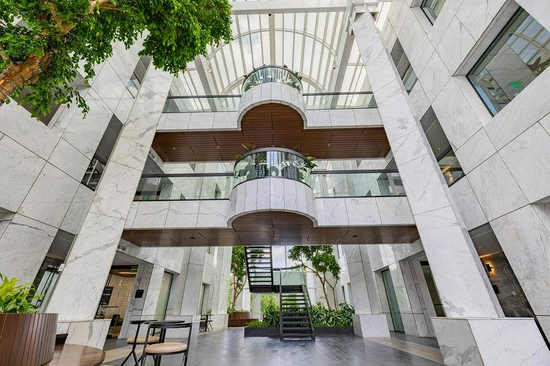 Grand multi-story atrium lobby with marble walls, indoor trees, and a central staircase.