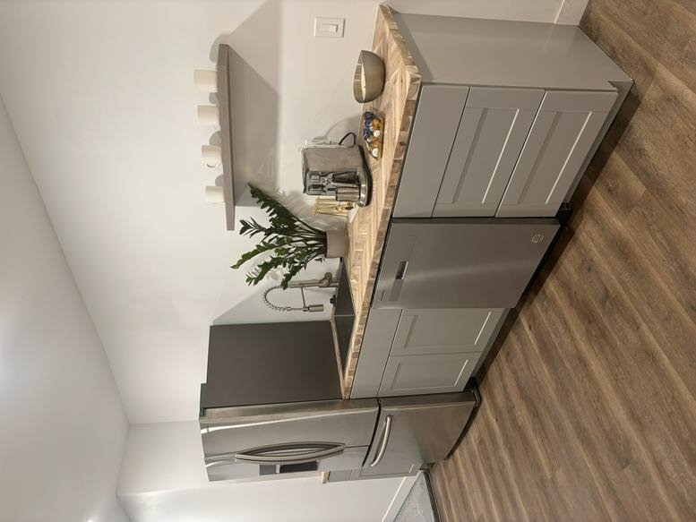 Compact kitchen area with light grey cabinets and a stainless steel refrigerator.