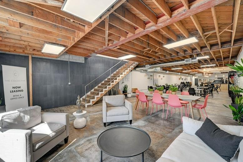 Open-plan lounge at 511 S Las Vegas Blvd with pink chairs, grey sofas, and a staircase.