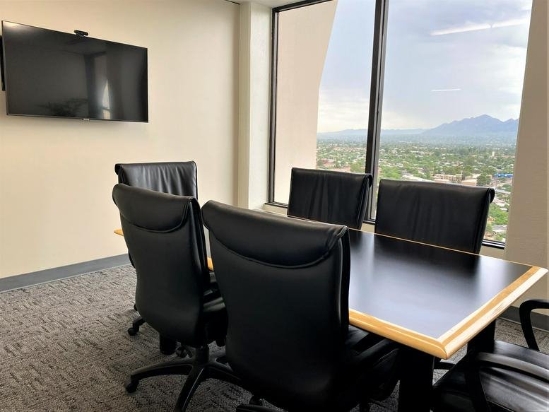 Meeting space featuring black leather chairs, a rectangular table, and a large window with mountain views.