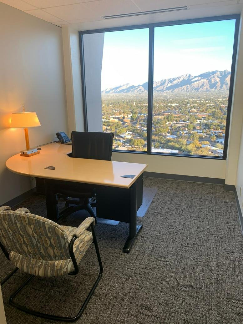 Private office with an L-shaped desk and a expansive window view of the Tucson mountain range.