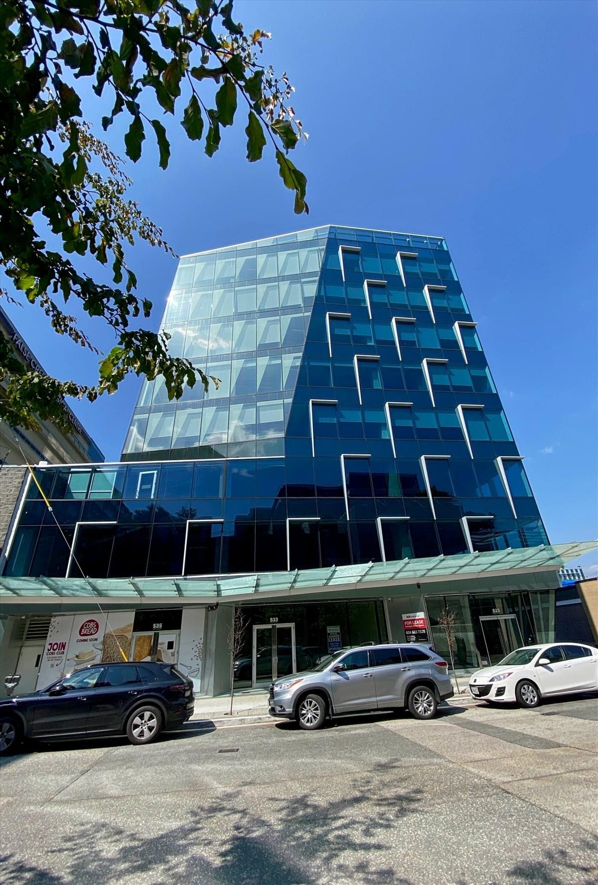 Full view of the contemporary blue glass office building at 525 West 8th Avenue.