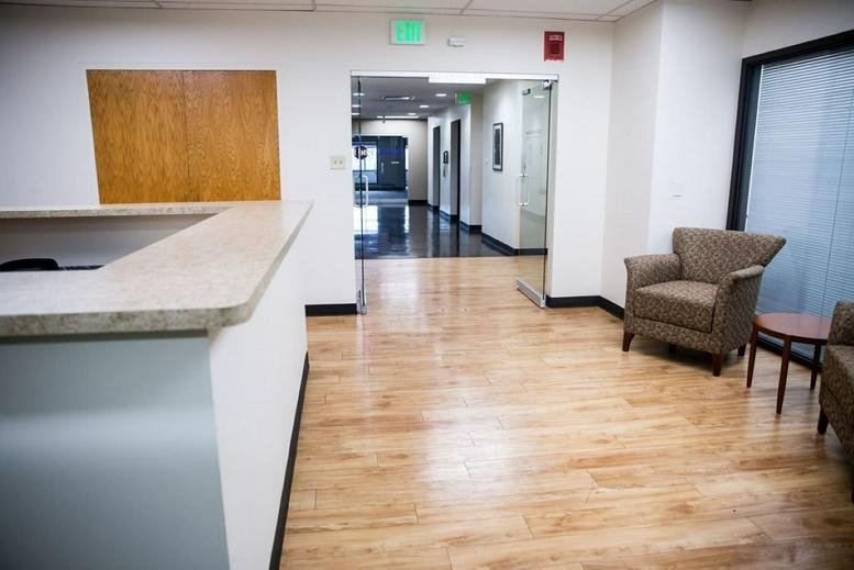Bright reception area at 5353 West Dartmouth Avenue, Suites 302 & 400 with wood flooring and a green exit sign.