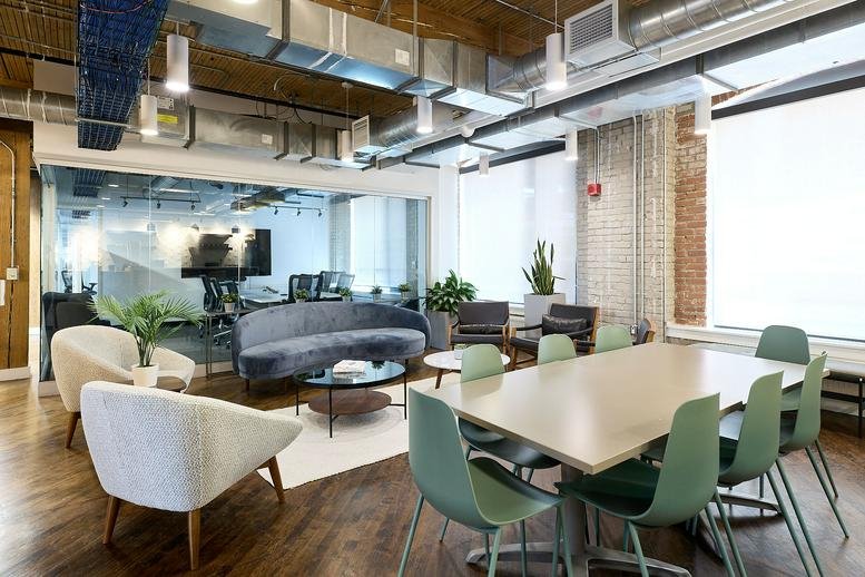 Spacious communal lounge at 545 King Street West with a large table, velvet sofa, and exposed ceilings.