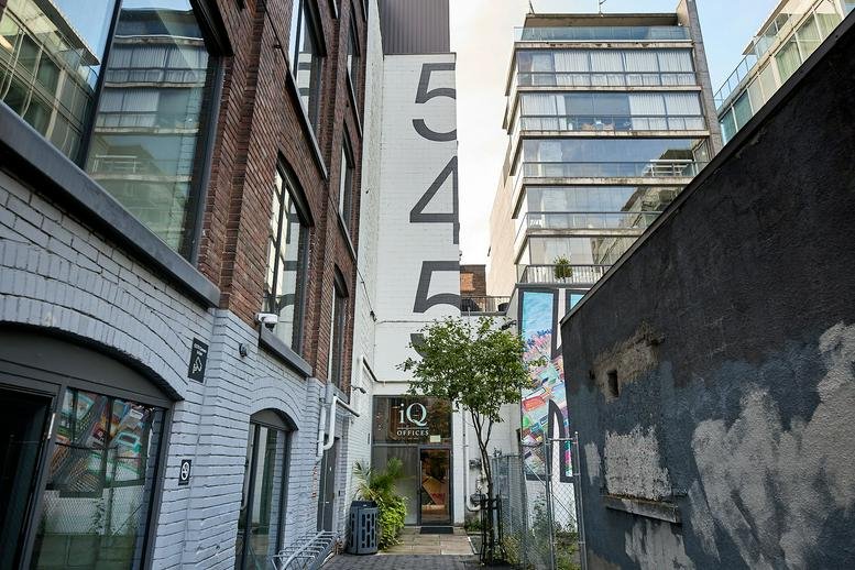 Street view of the entrance at 545 King Street West, Toronto, nestled between brick and glass buildings.