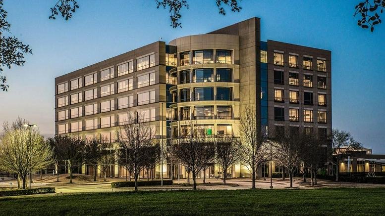 Dusk exterior shot showing the office building fully illuminated with warm interior lights.