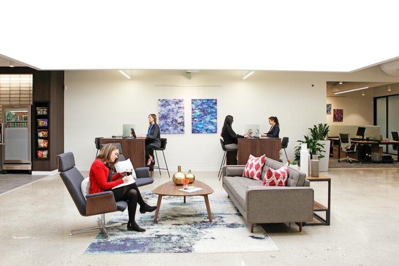 Spacious communal lounge with diverse seating, a large area rug, and abstract blue wall art at 55 Post Road West.