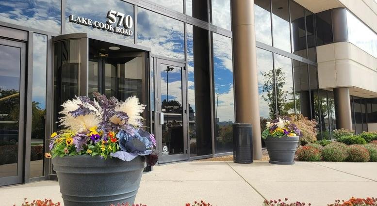 Exterior view of the glass entrance and flower-lined walkway at 570 Lake Cook Road.