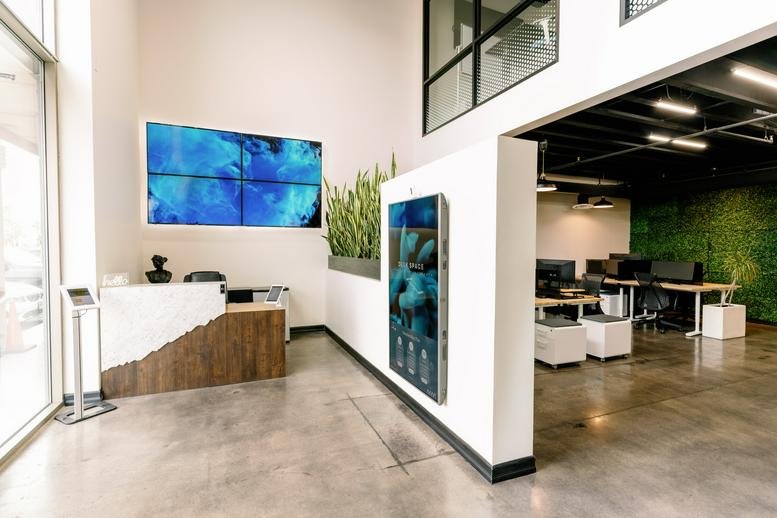 Modern reception area with wood-fronted desk and large digital display wall.