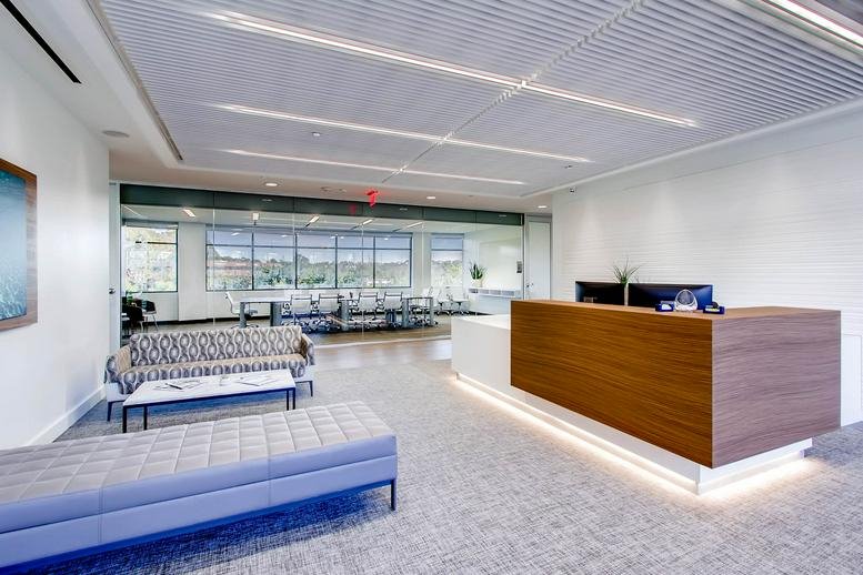 Bright reception area at 5857 Owens Avenue, Suite 300 with a wood-paneled desk and lounge seating.