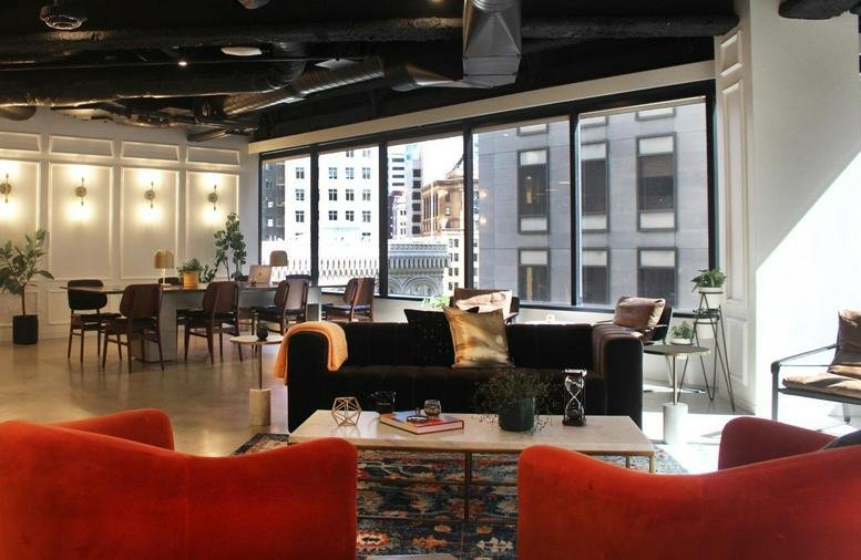 Spacious communal lounge at 595 Market Street, 10th Floor, with velvet armchairs and large windows.