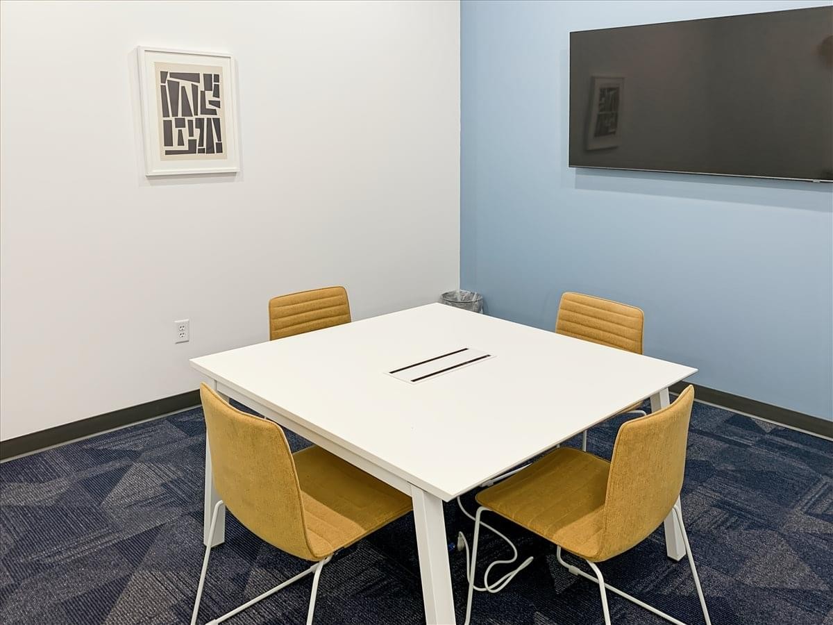Meeting room at 6044 South 16th Street, 1st Floor featuring a white square table and four yellow chairs.