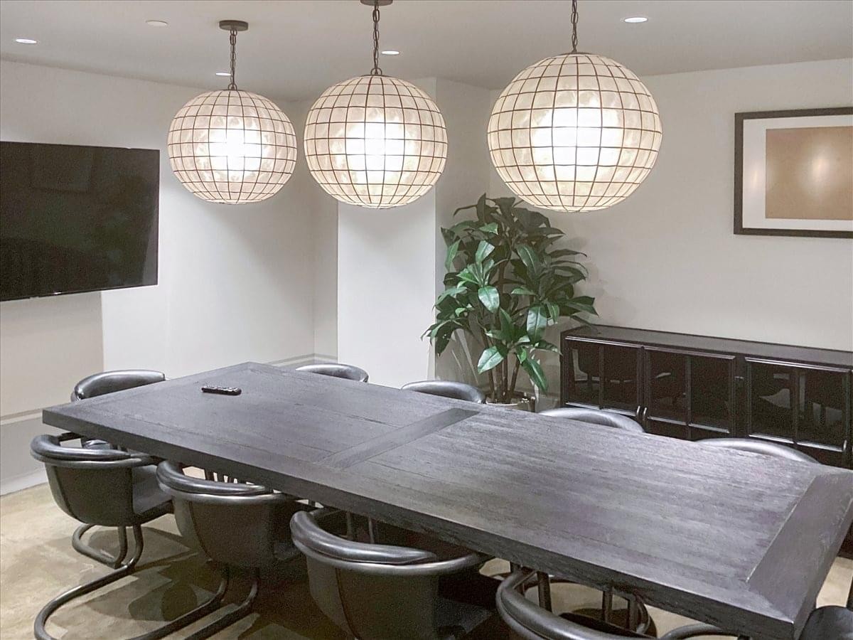 Spacious boardroom with a large black table and three spherical pendant lights at 609 H Street Northwest.