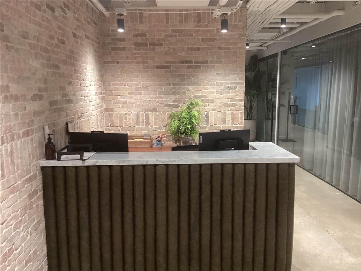 Sleek reception area at 609 H Street Northwest with a wood-slat desk and an exposed brick feature wall.