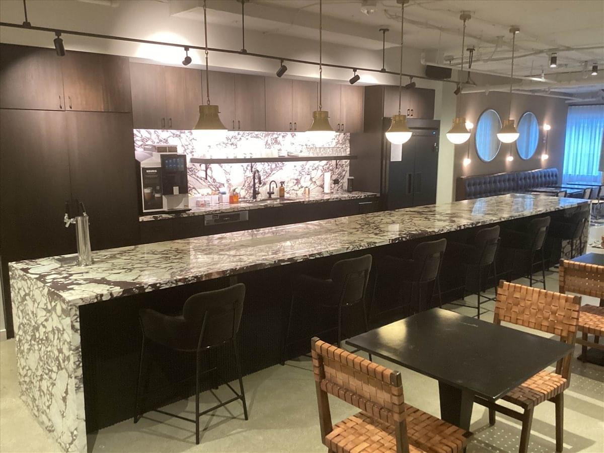Spacious communal kitchen and cafe area with a marble breakfast bar and woven chairs.