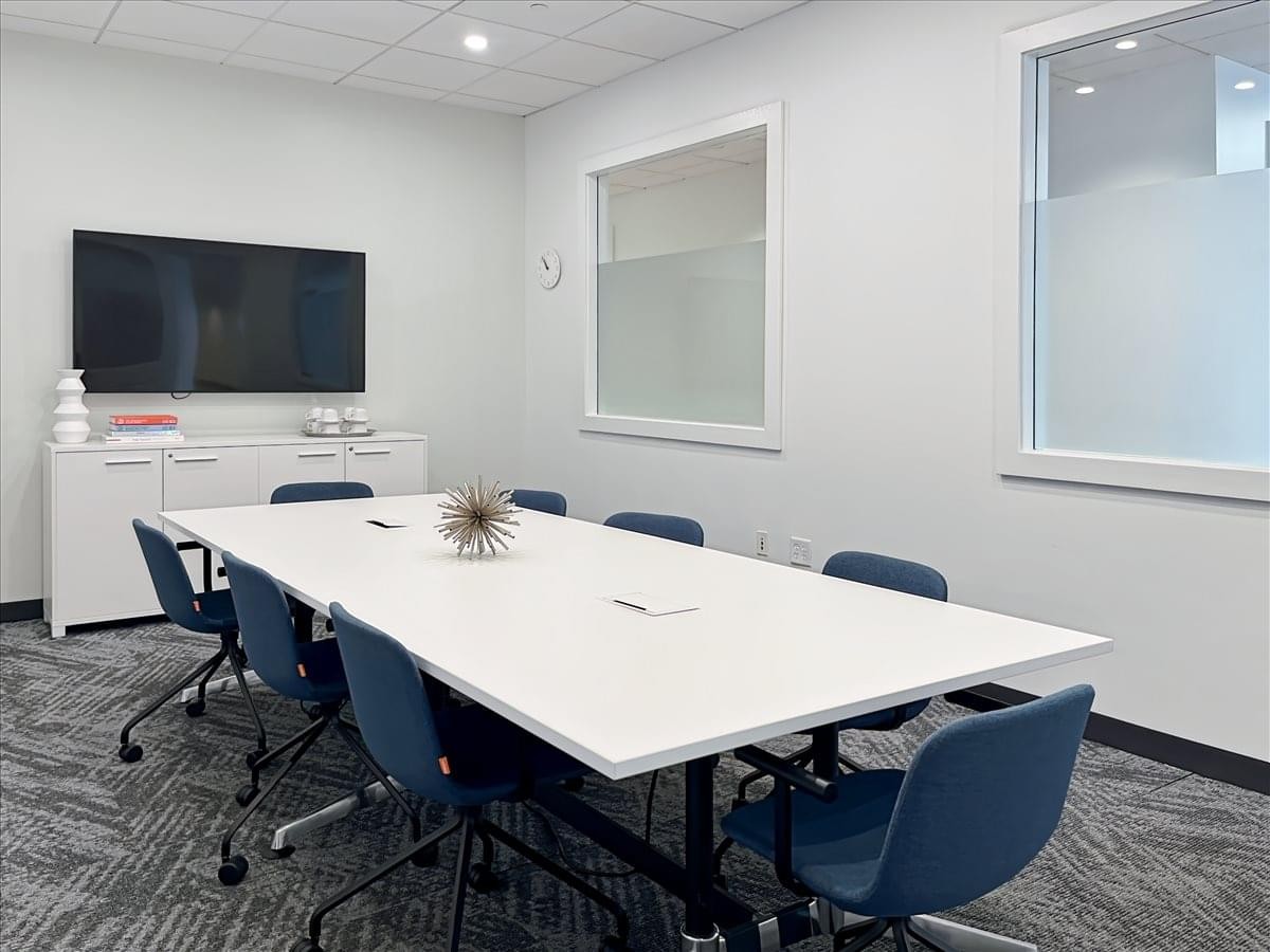 Meeting room at 61 West Palisade Avenue, 2B, Englewood with a white conference table, blue chairs, and a wall-mounted TV.