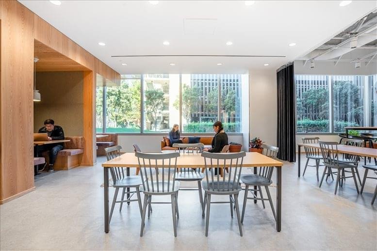 Industrial-style lounge with diverse seating options and large windows showing city greenery.