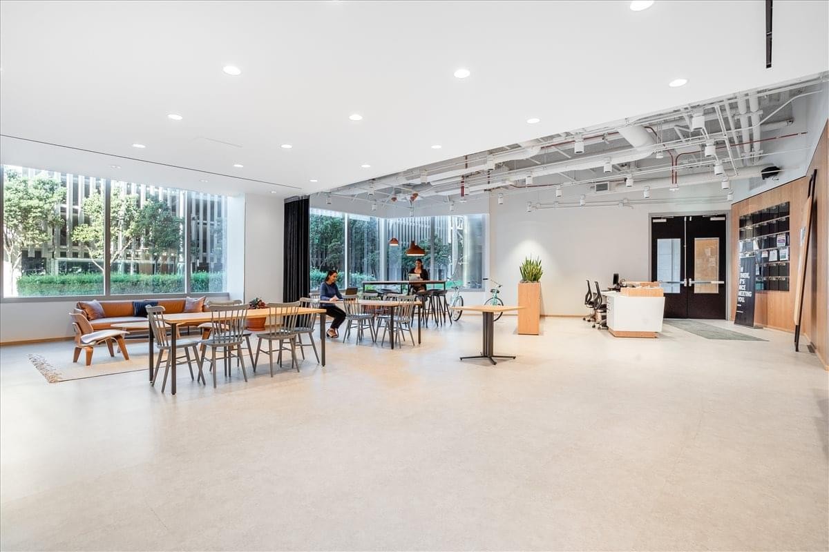 Bright lobby of 611 Gateway Boulevard featuring a white desk and industrial ceiling.