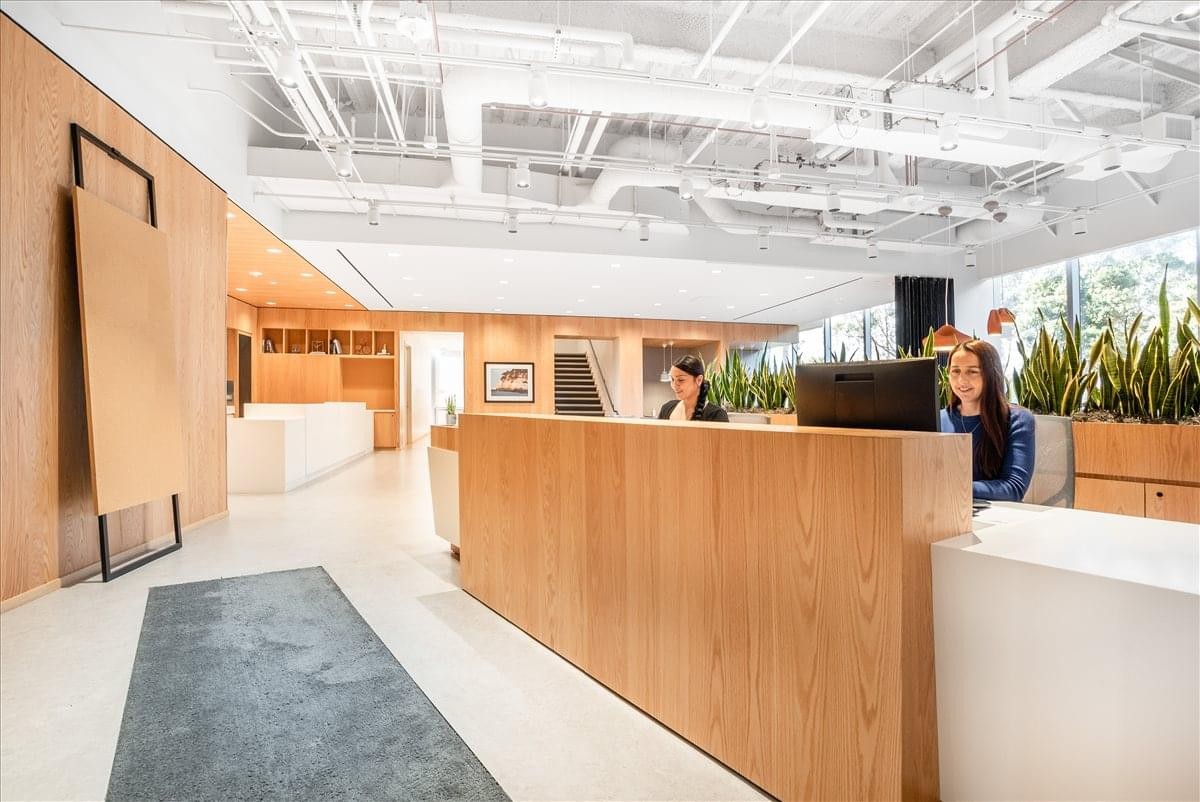 Wooden reception desk at 611 Gateway Boulevard, Suite 120 with industrial white ceiling pipes.