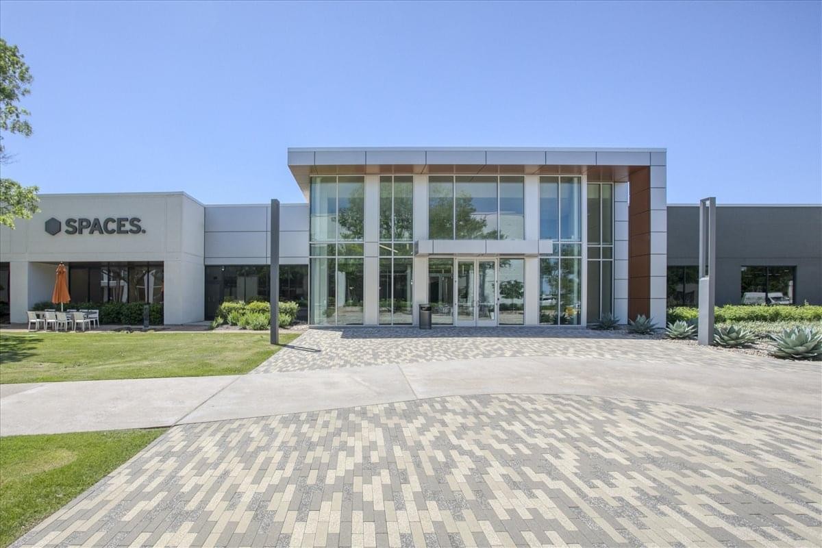 Modern exterior of the 6600 Chase Oaks Boulevard building featuring a glass-fronted entrance and manicured lawn.