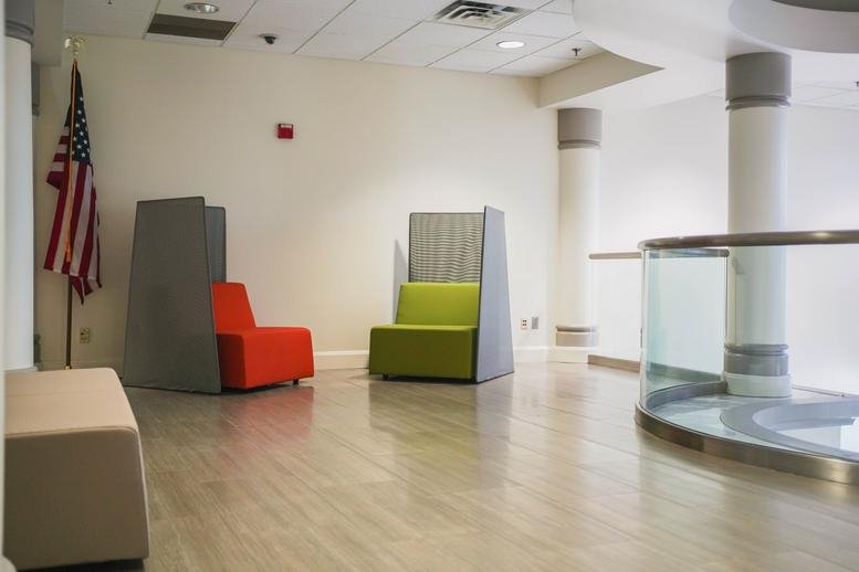 Lounge area at 6601 Park of Commerce Boulevard with colorful modern seating and an American flag.