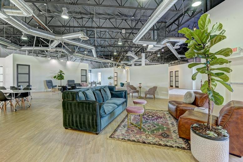 Spacious communal lounge at 6675 S Tenaya Way, ste 200, with velvet sofas, rugs, and industrial ceilings.