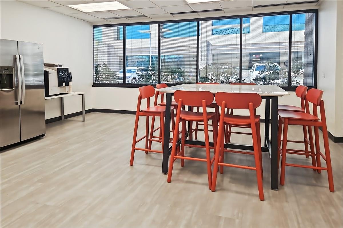 Spacious communal breakroom at 6710 North Scottsdale Road, 1st Floor featuring red high-top seating and floor-to-ceiling windows.