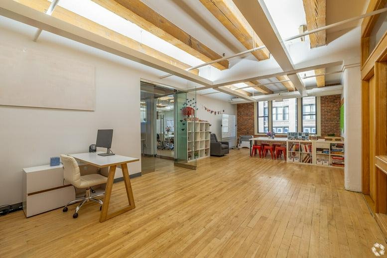 Bright open-plan office at 68 Harrison Avenue with timber beams and hardwood flooring.
