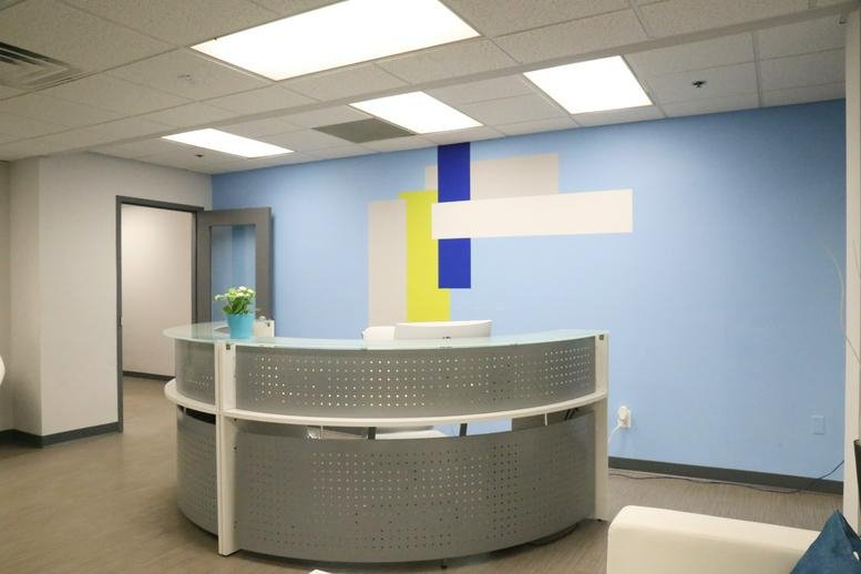 Bright reception area at 6811 Kenilworth Avenue, Suite 500 featuring a curved desk and colorful geometric wall art.